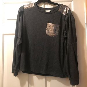 a dark long sleeve shirt with a sequin pocket and the shoulders have sequins